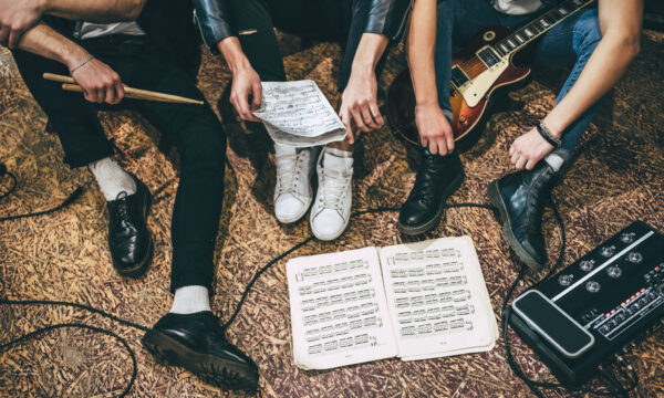 Music band repetition Repetition of rock music band. Cropped image of guitar players and drummer are sitting on the floor at rehearsal base with notes. Top view
