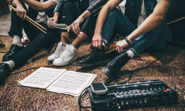 Music band repetition Repetition of rock music band. Cropped image of guitar players and drummer are sitting on the floor at rehearsal base with notes.